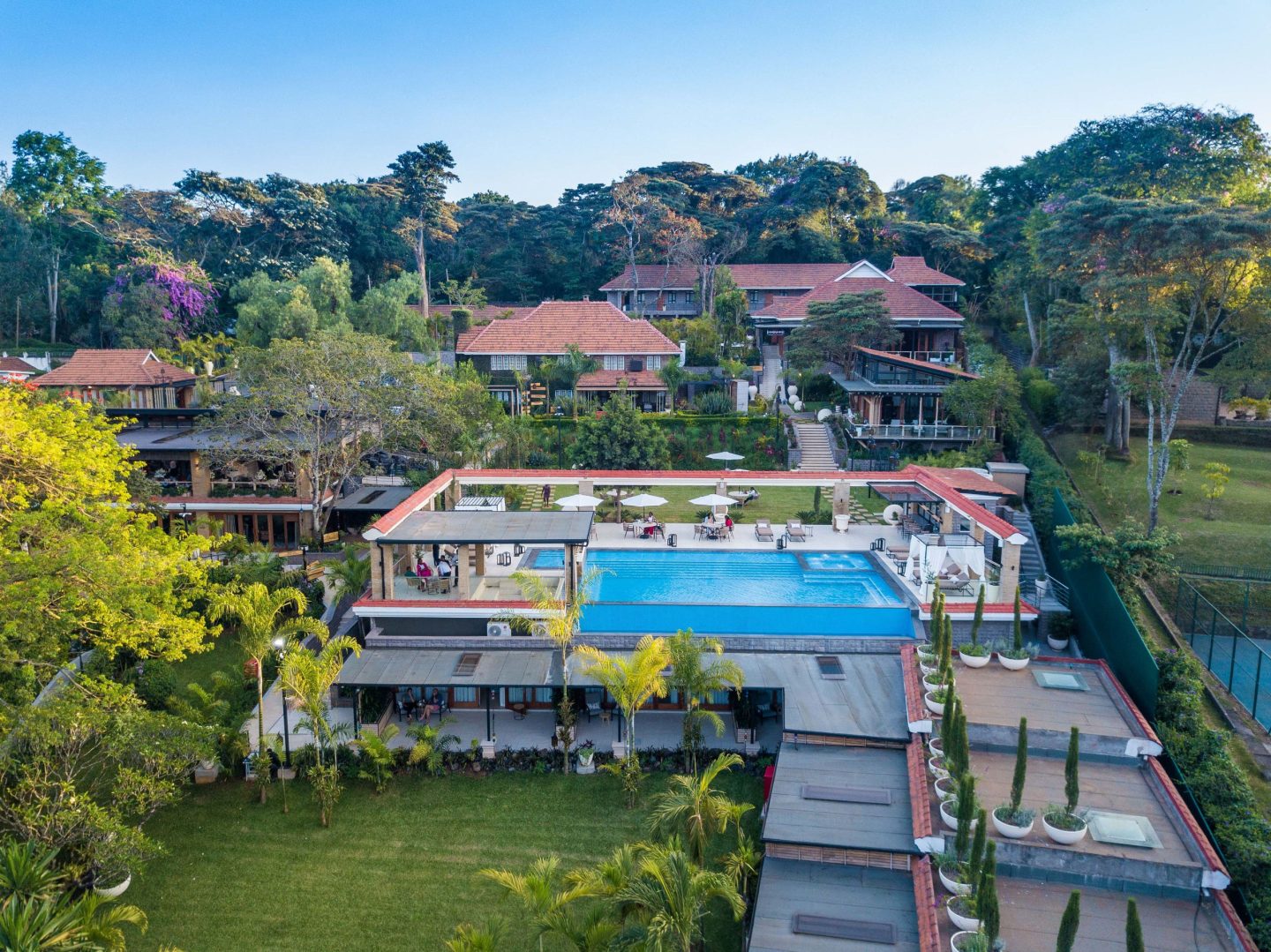 A lodge and its pool set among mature trees, seen from the air