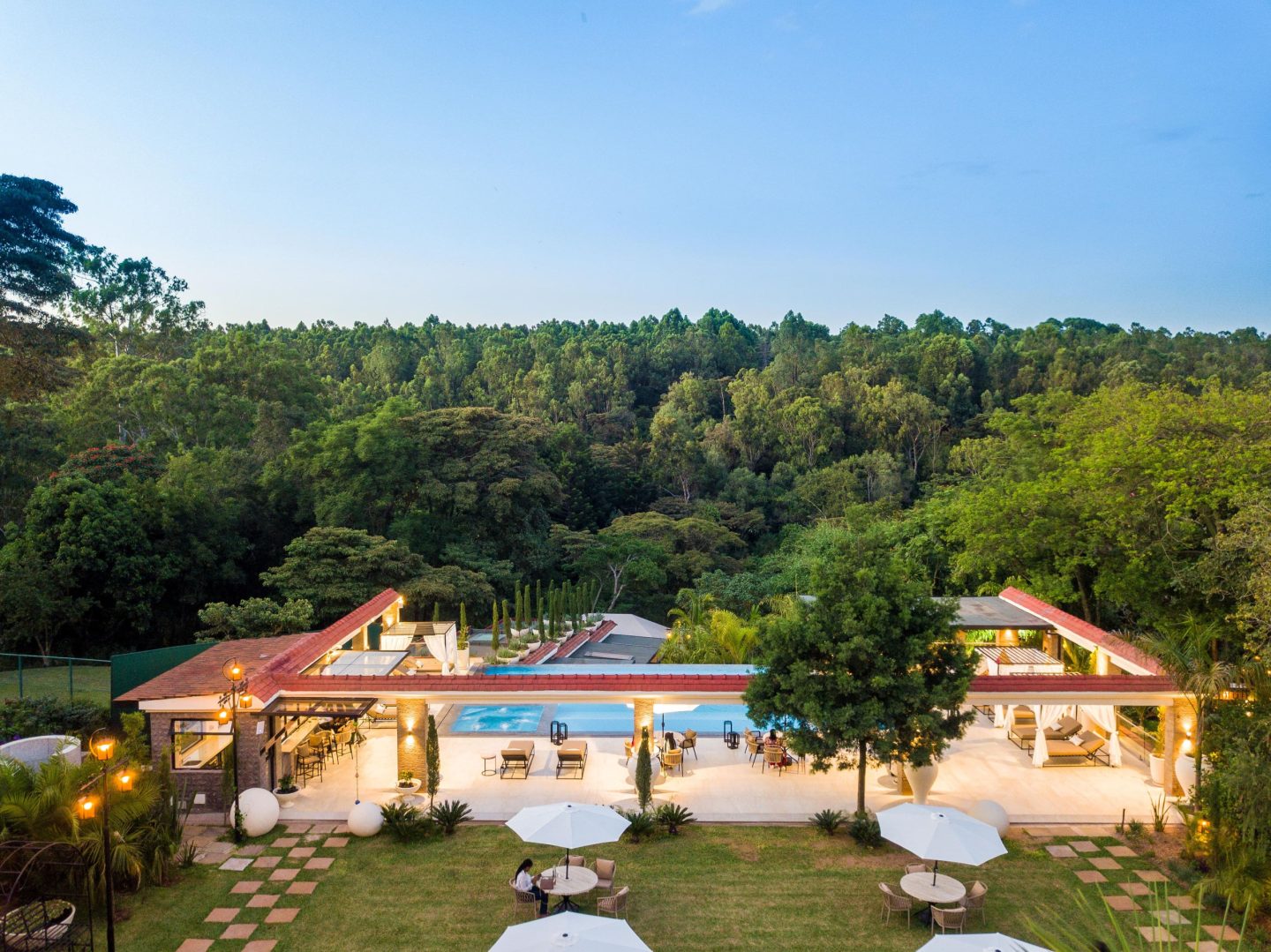 A lit pool in front of a lodge building at dusk